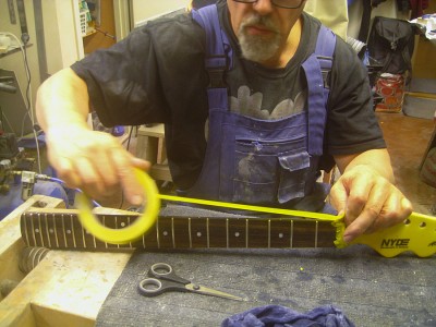 Masking the fretboard before spraying lacquer.