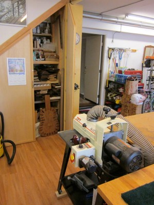 Looking to the right of that last high bench, you can see the sander and the storage cabinet with one door open. Clock pencil sharpener, lacrosse sticks, etc.